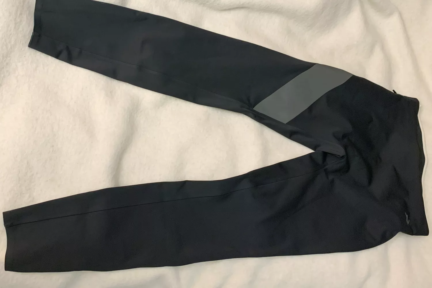Tracksmith Menâs NDO Tights laid out on a bed
