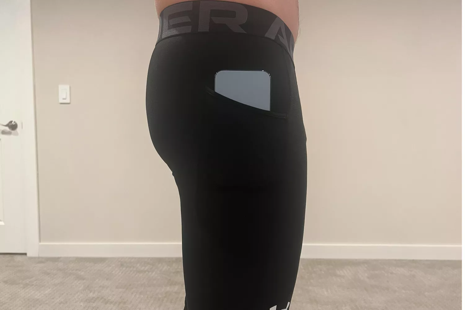 Person with their phone in the pocket of Under Armour Men's HeatGear Leggings