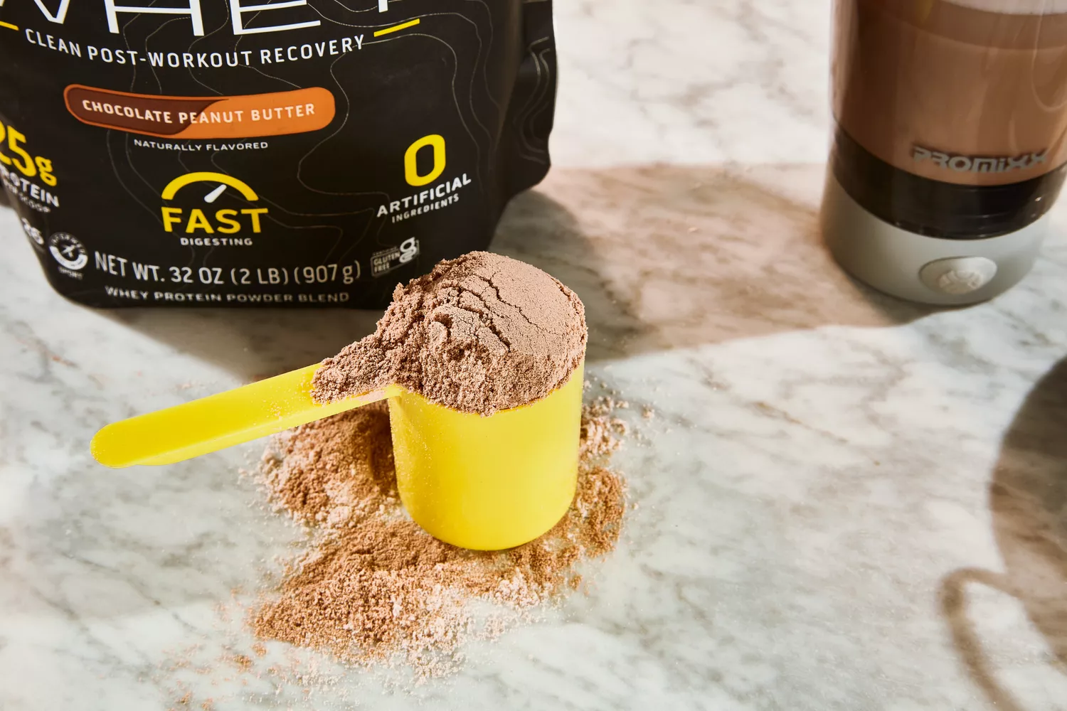 Scoop of Ascent Native Fuel Whey Protein Powder displayed in front of its packaging