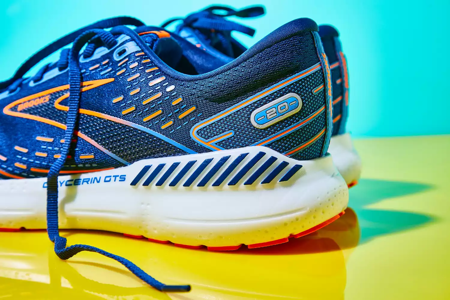 A close up of the heel of the Brooks Men's Glycerin GTS 20 Running Shoes on yellow and teal backdrop