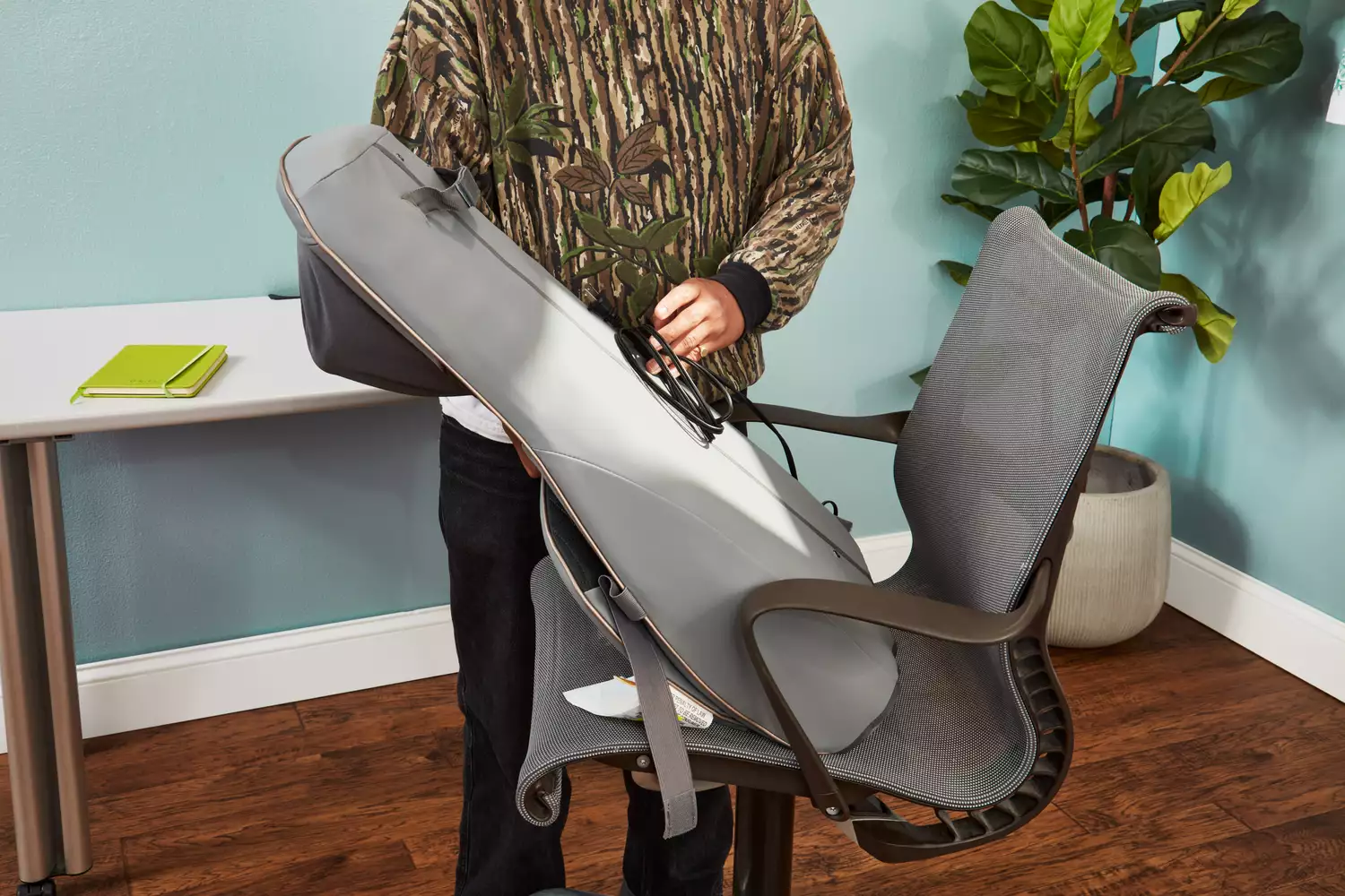 A person holding a Homedics Shiatsu Elite II Massage Cushion with Heat near a desk chair