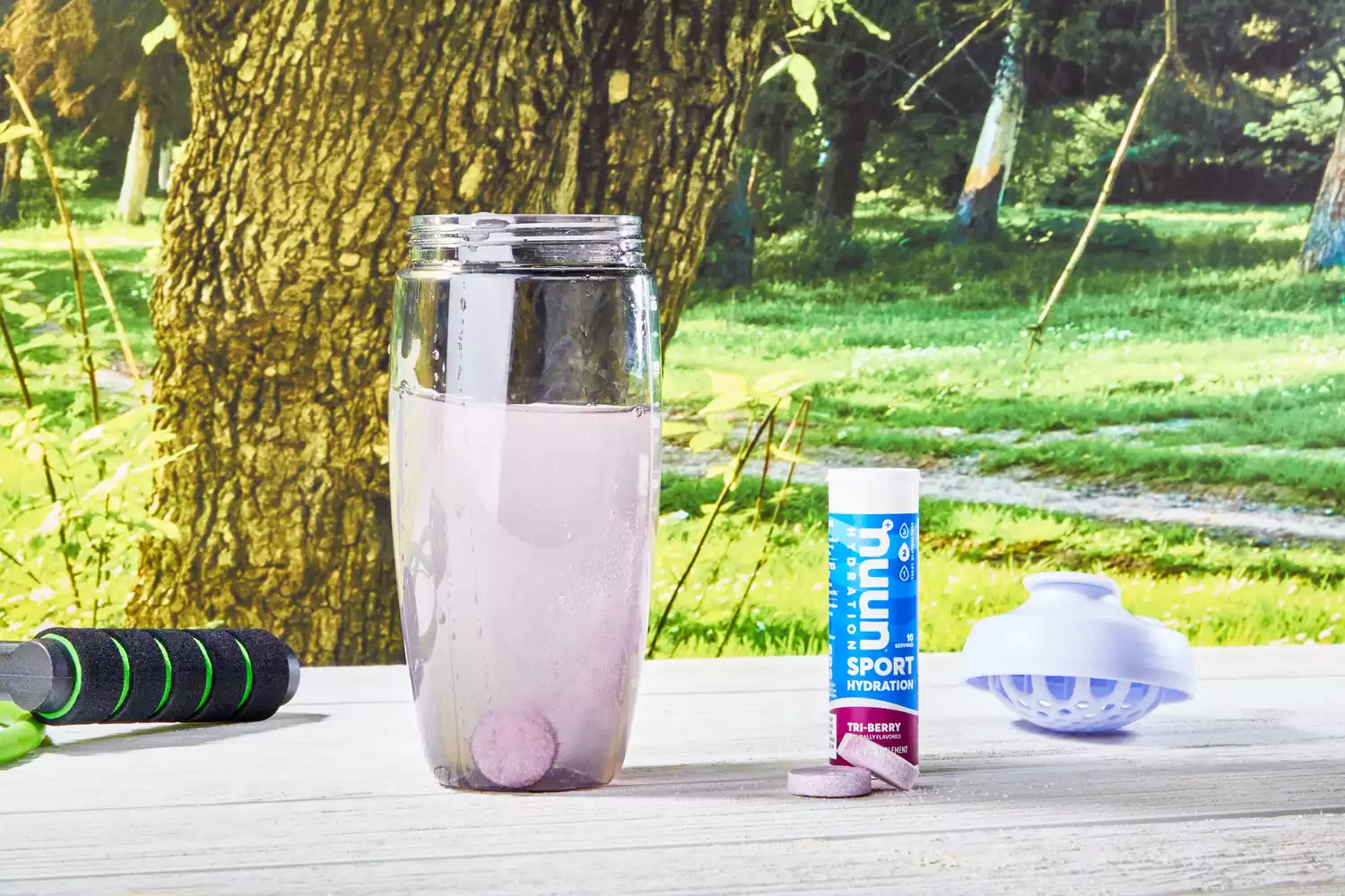 A Nuun Sport Electrolyte Drink Tablet dissolving in a glass of water in an outdoor setting