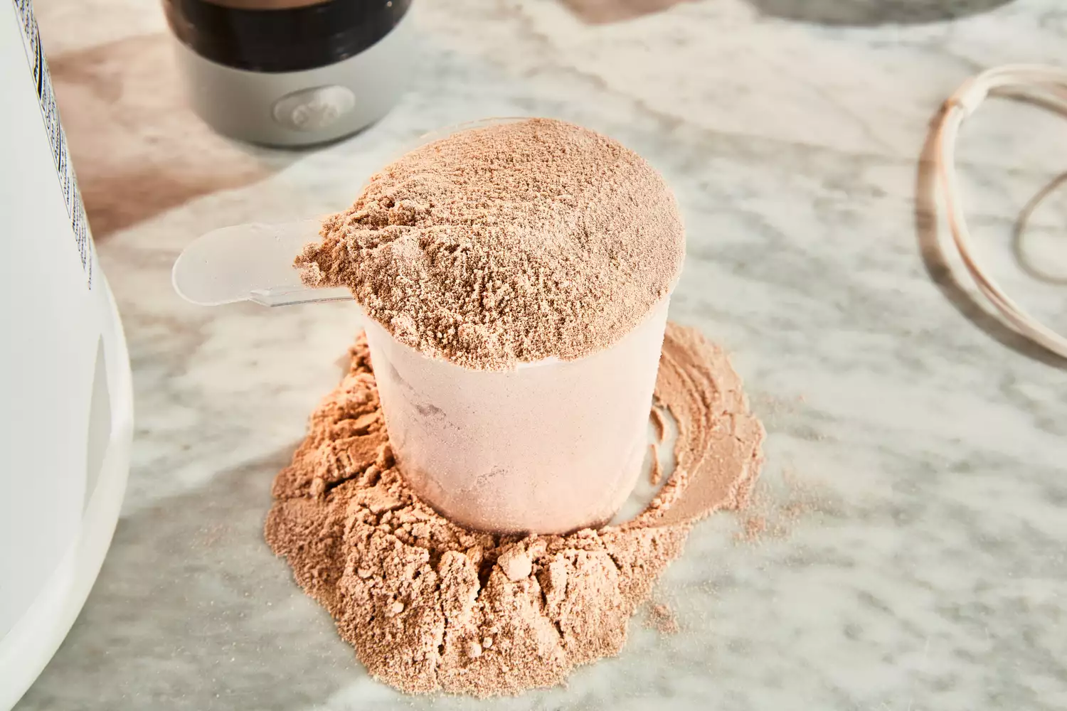 Overflowing scoop of protein powder on marble counter