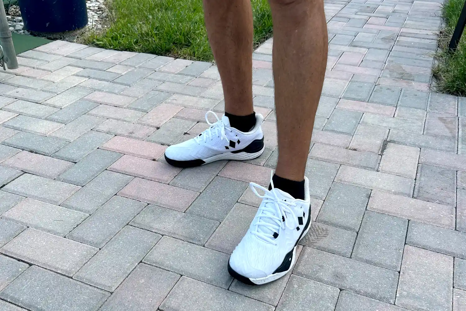 A person wears the Diadem Court Burst Pickleball Shoes on brick