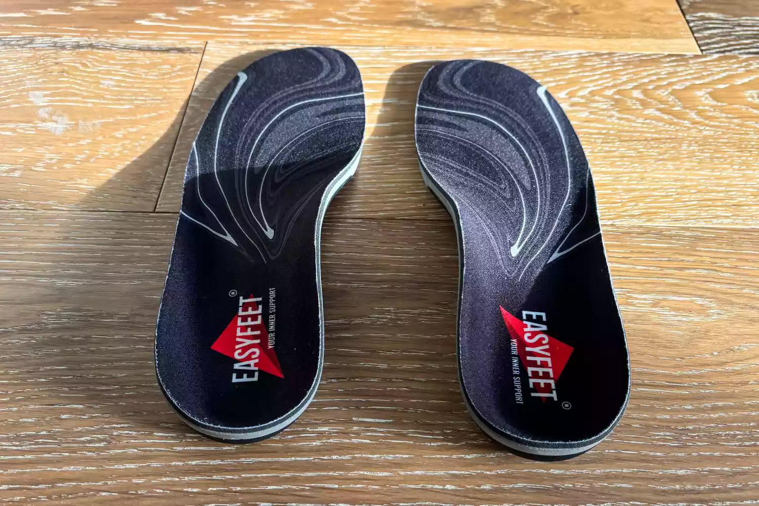 The EasyFeet Black Onyx Pain Relief Premium Orthotics on a wooden floor