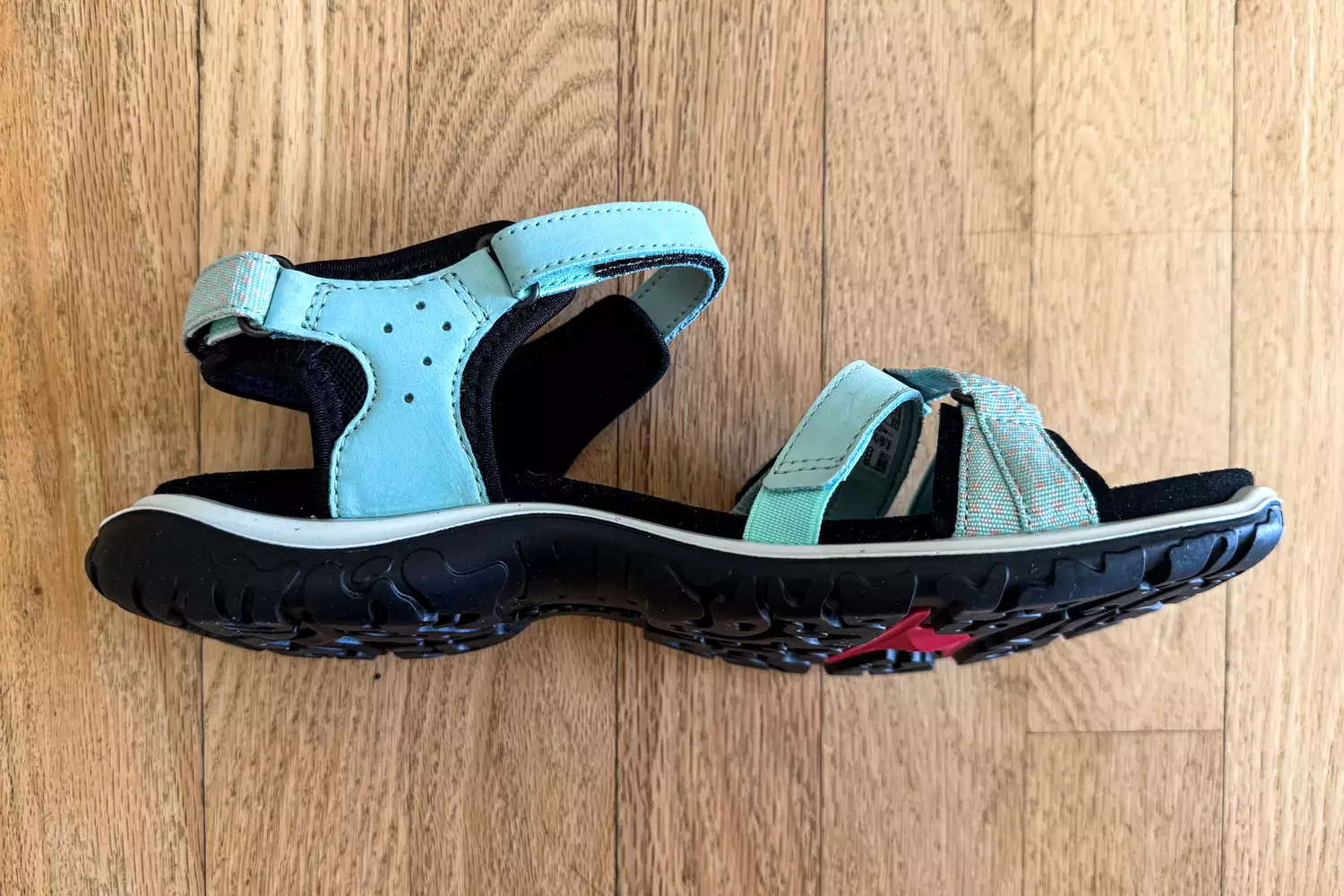 A ECCO Offroad Roam Women's Nubuck Outdoor Sandal laying on its side on wood