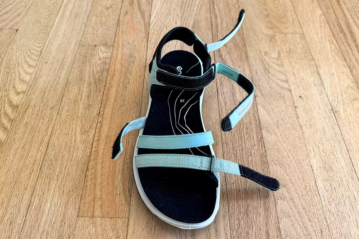 A ECCO Offroad Roam Women's Nubuck Outdoor Sandal woth straps opened on a wooden floor