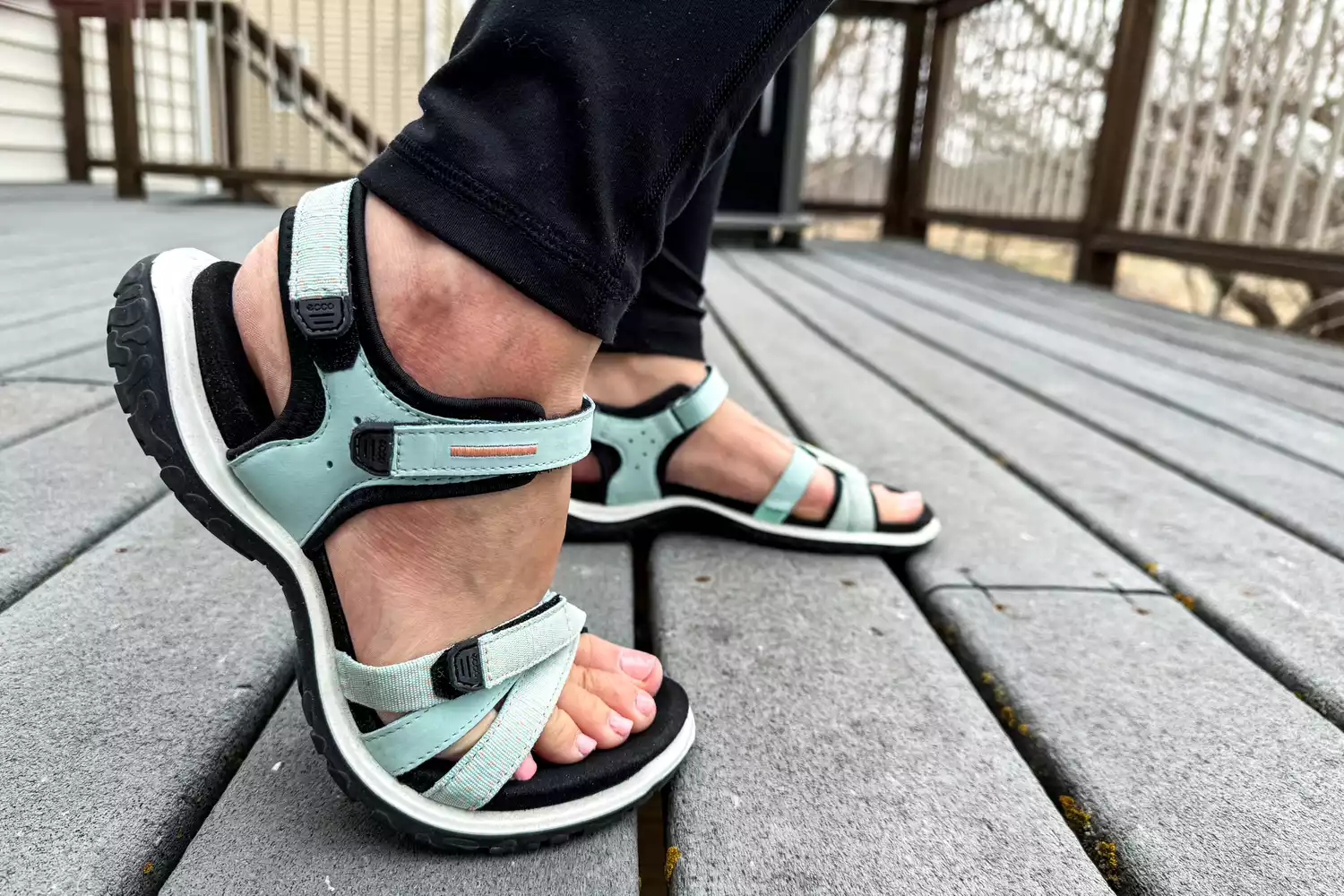 A side view of posed feet in the ECCO Offroad Roam Women's Nubuck Outdoor Sandal on a deck