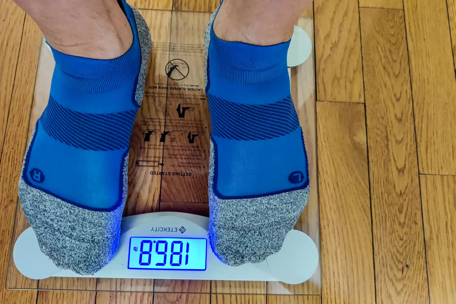 A person stands on the Etekcity EB4074C Digital Body Weight Scale in socks