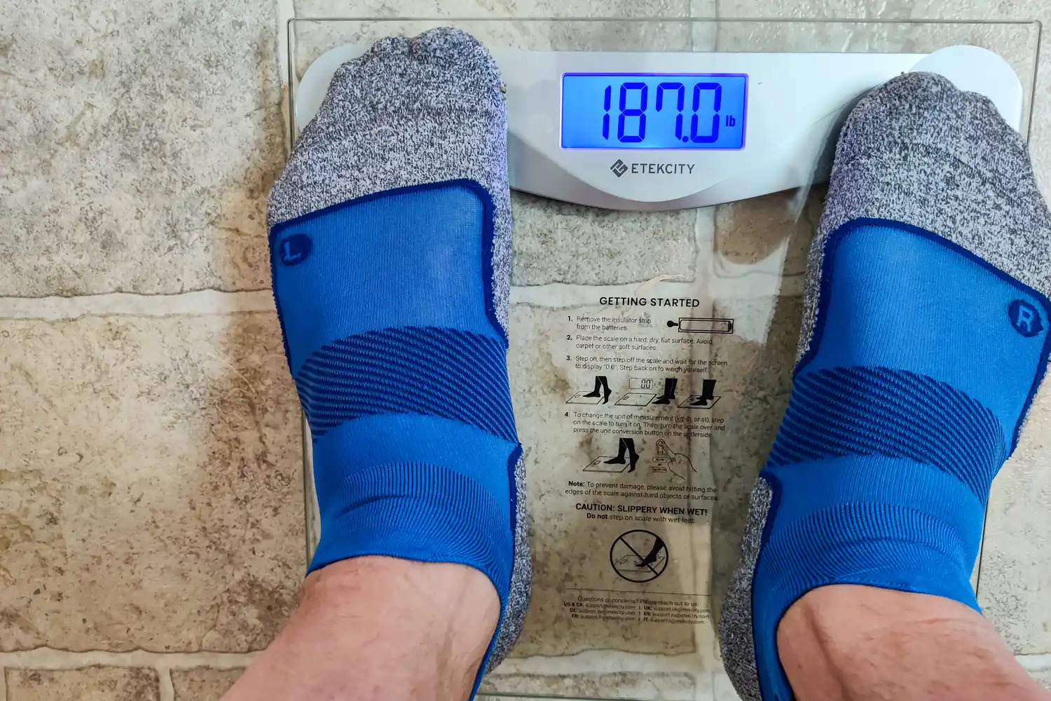 A person stands on the Etekcity EB4074C Digital Body Weight Scale in socks