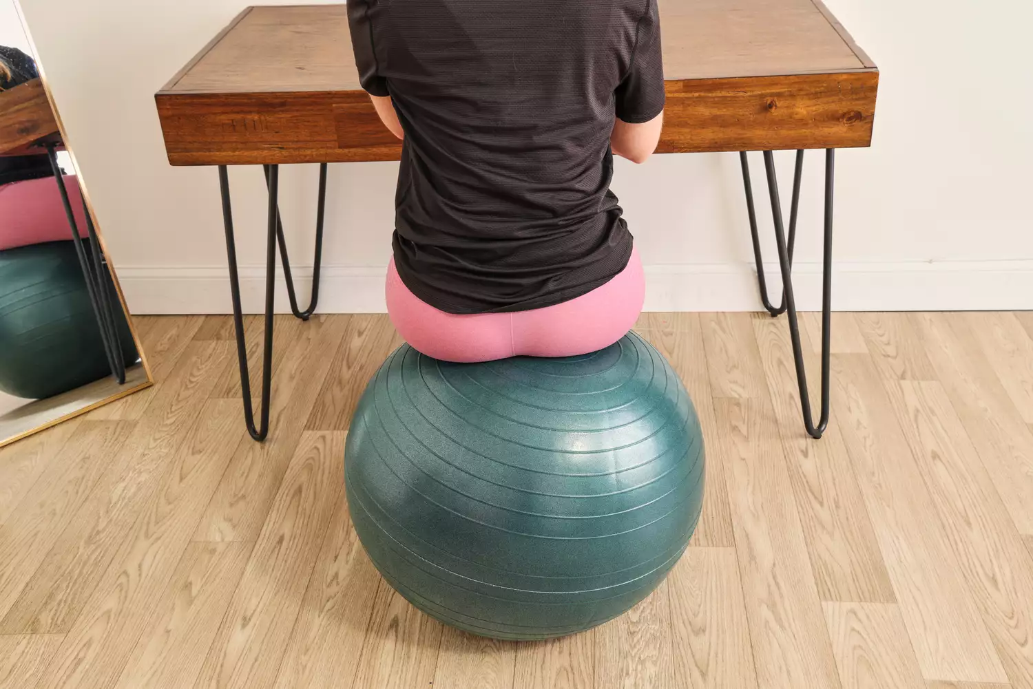 A person sits on the Power Systems Versa Ball Pro Stability Ball