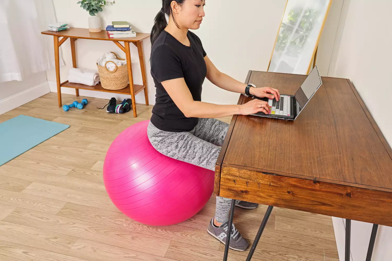 A person types on a laptop while sitting on the SmarterLife Workout Exercise Ball