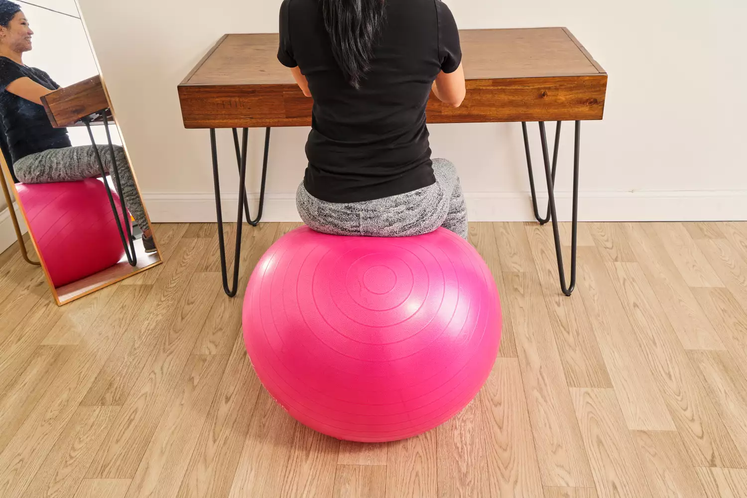 A person sits on the SmarterLife Workout Exercise Ball while typing on a laptop