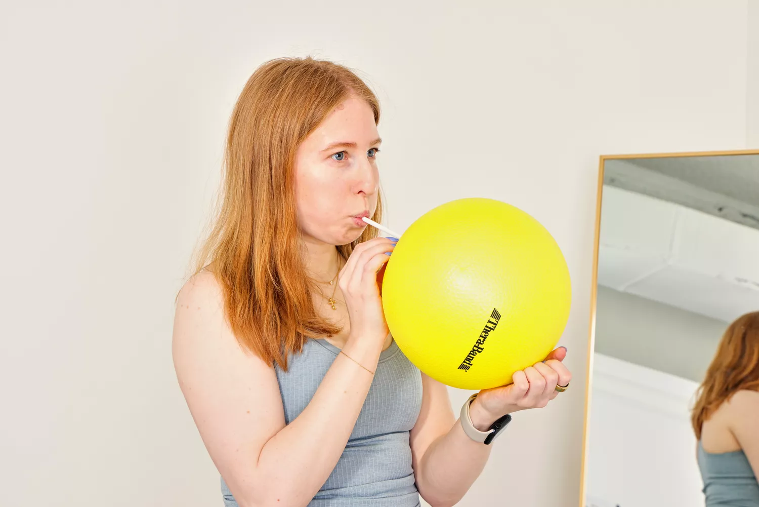 A person inflates the Theraband Mini Exercise Ball using a straw