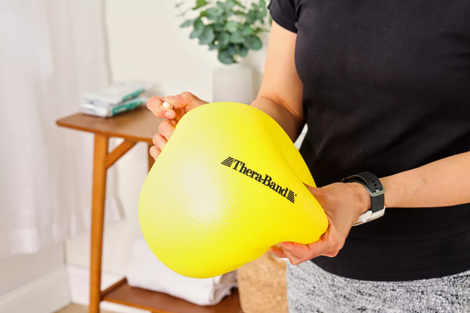 A person deflates the Theraband Mini Exercise Ball