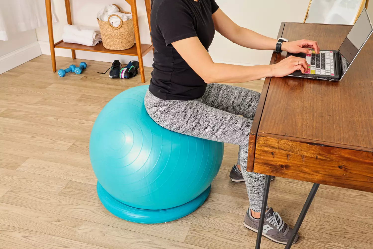 A person sits on the Trideer Exercise Ball Chair while typing on a laptop