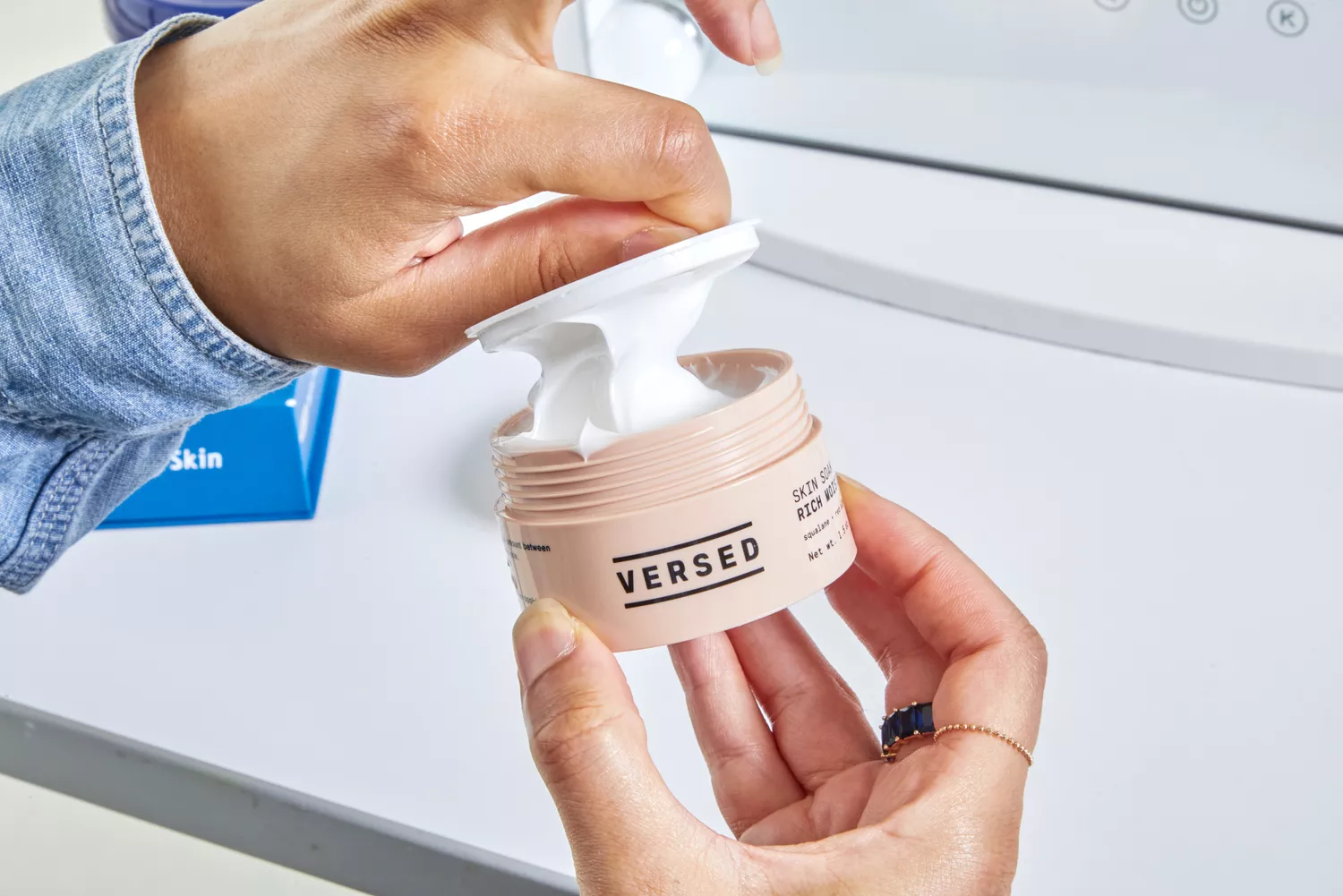 Person opening a lid of Versed Skin Soak Rich Moisture Cream