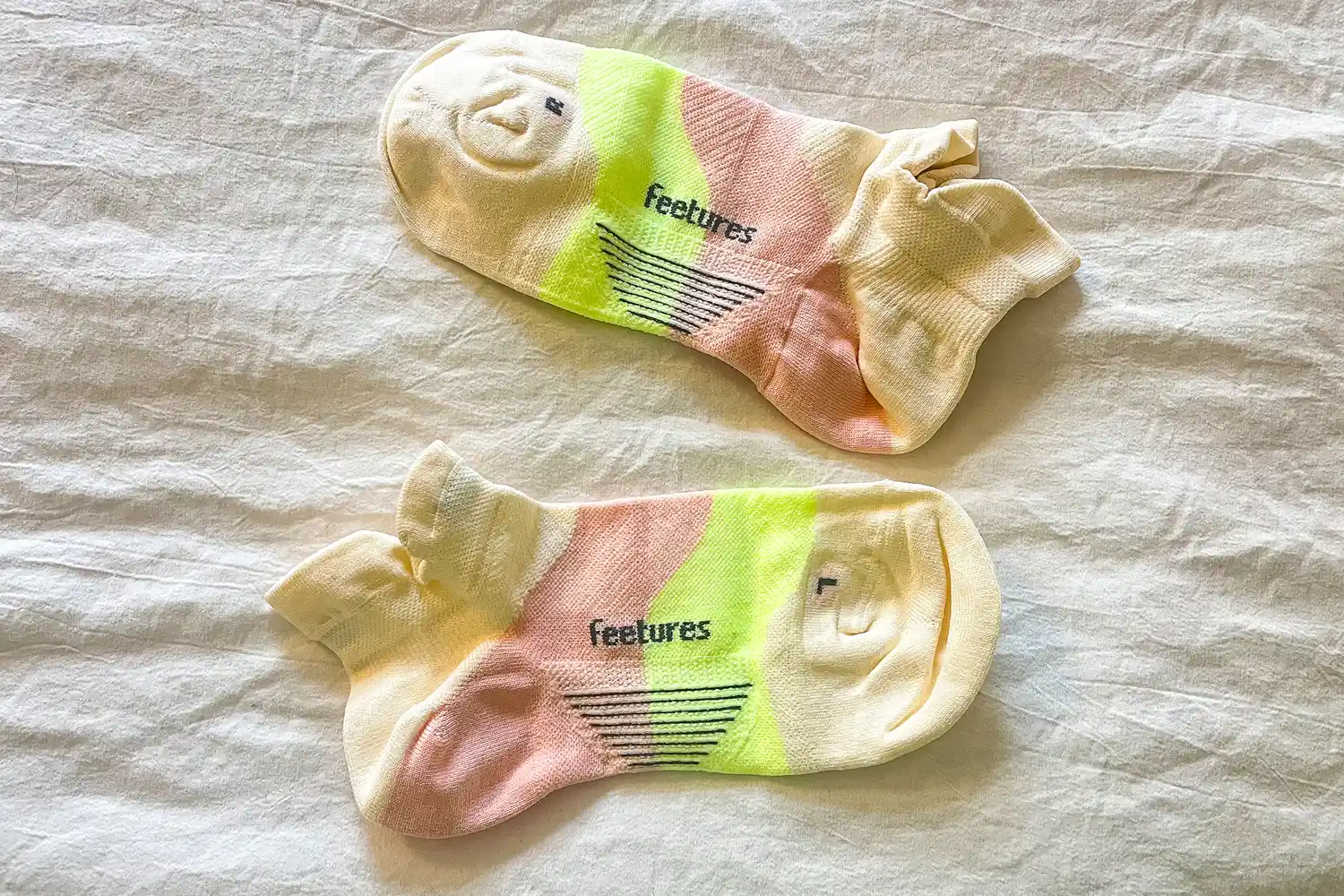 A pair of Feetures Elite Ultra Light Tab Socks on a white sheet