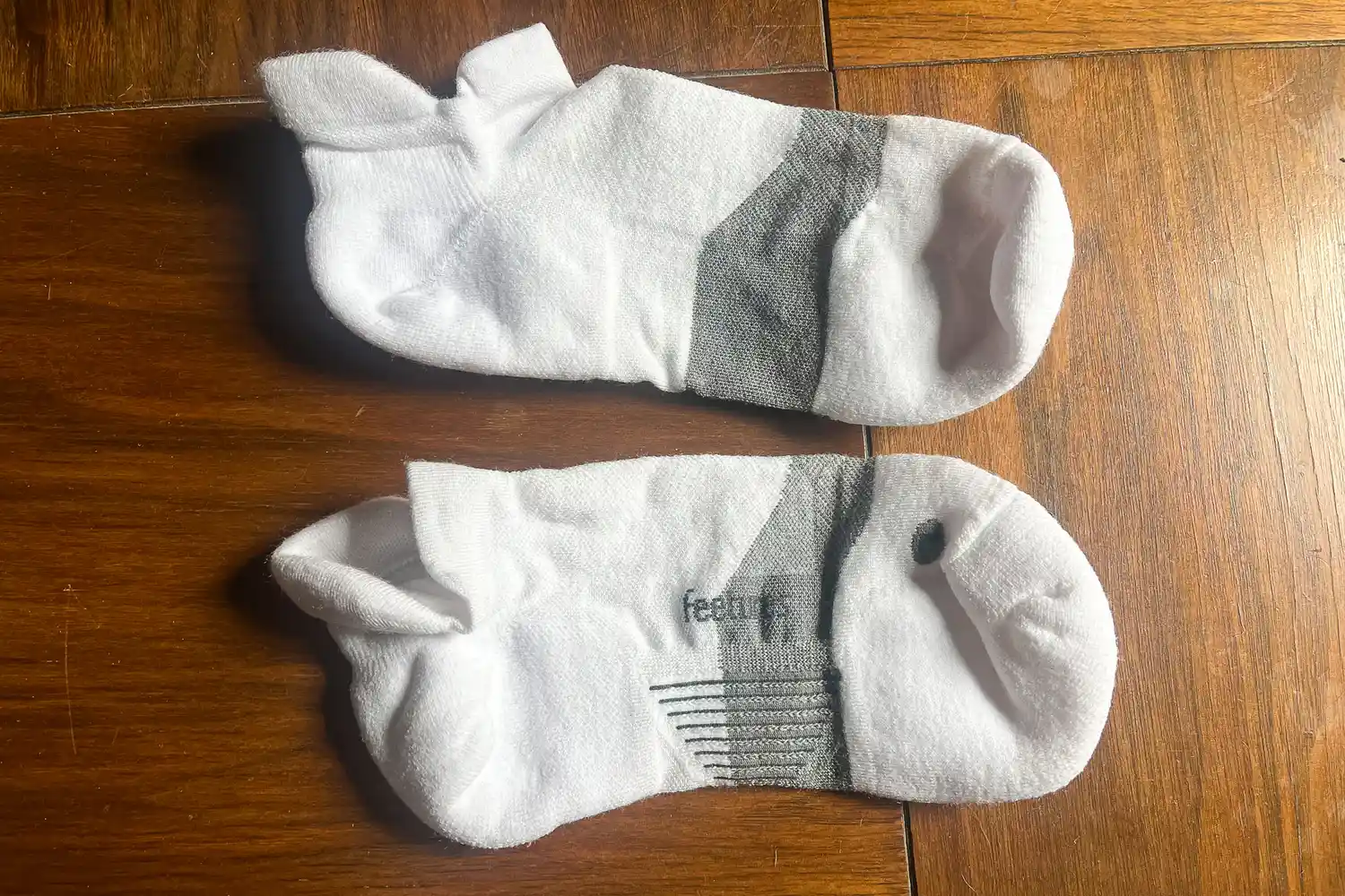 A pair of Feetures Merino 10 Max Cushion Tab Socks on a wooden floor