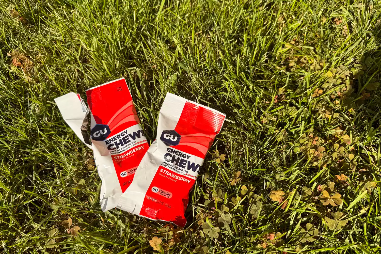 Two packets of GU Energy Chews on grass