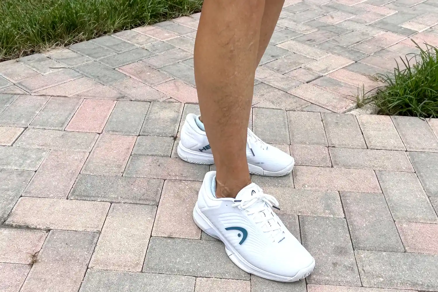 A person walks outside on brick while wearing the HEAD Women's Revolt Pro 4.5 Pickleball Shoes