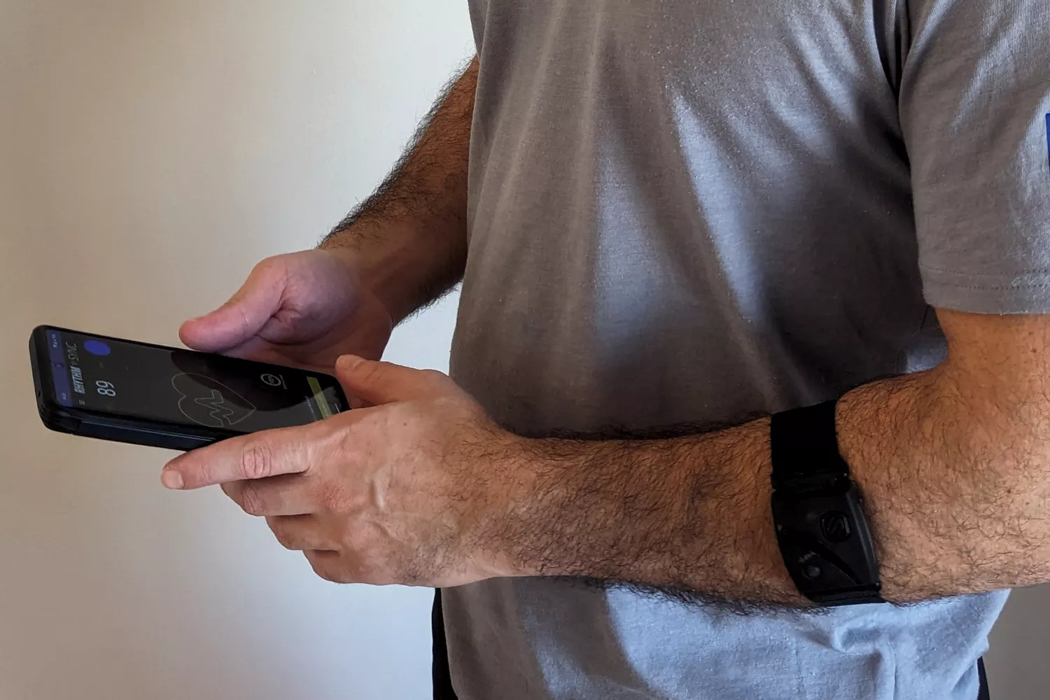 Person wearing a Scosche Rhythm24 Waterproof Armband Heart Rate Monitor while using the app