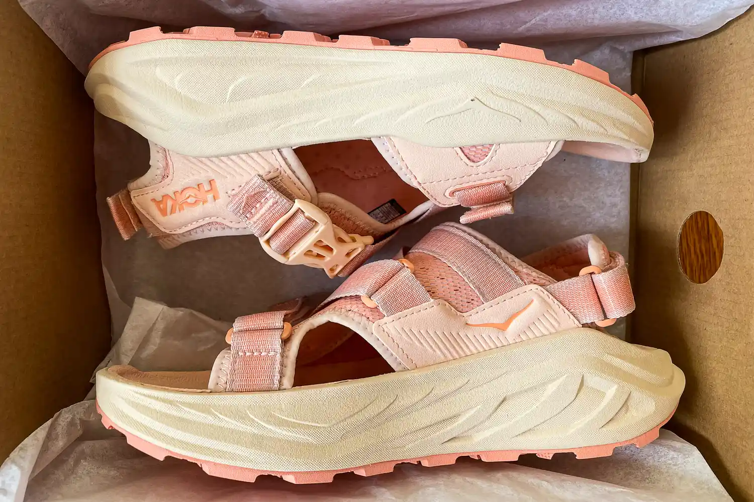 A side view of the HOKA Women's Infini Hike TC Sandals in a shoebox