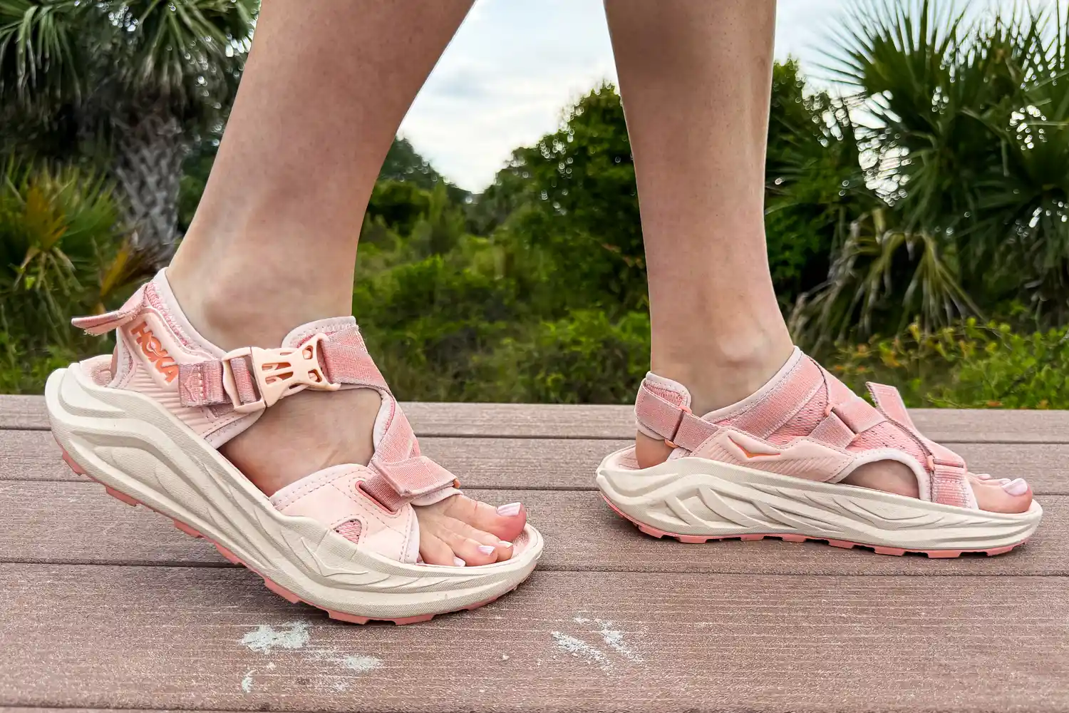 A person wears the HOKA Women's Infini Hike TC Sandals while walking outside