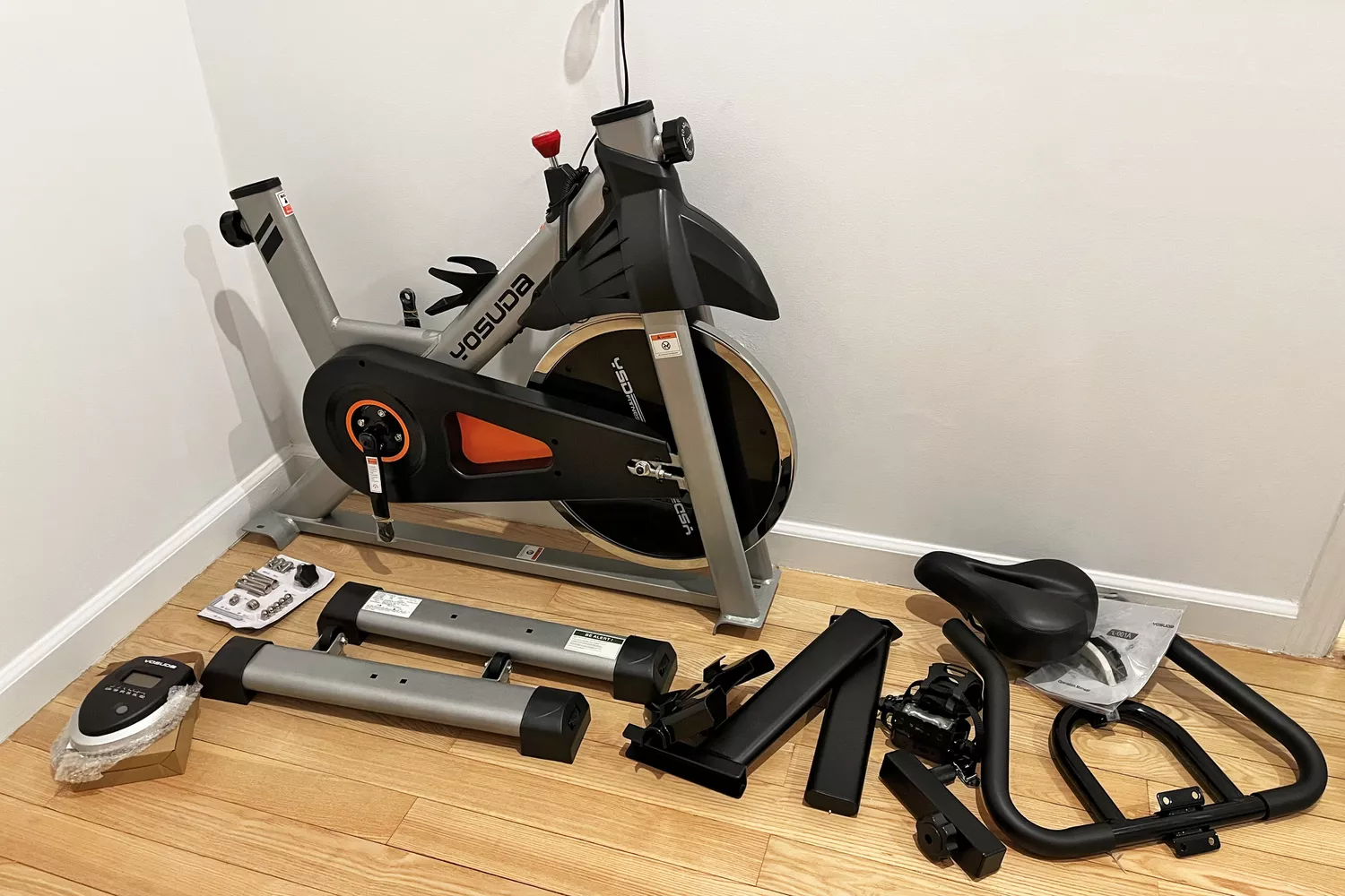 Disassembled YOSUDA Indoor Cycling Bike on a hardwood floor