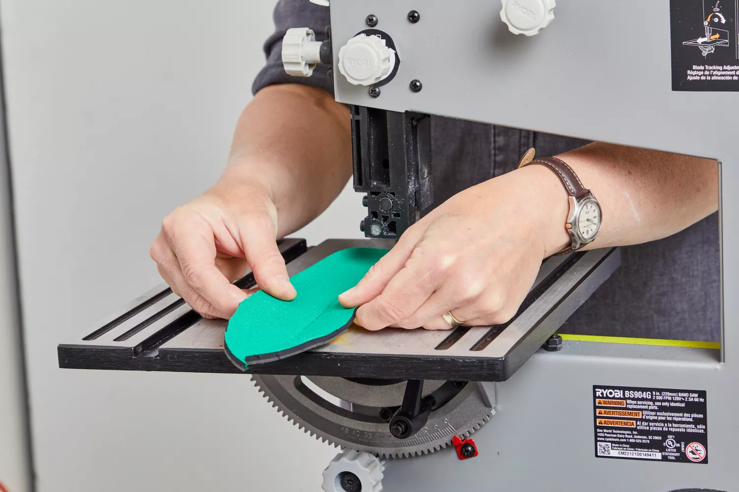 Hands using a machine to cut a Spenco PolySorb Cross Trainer Insole in half