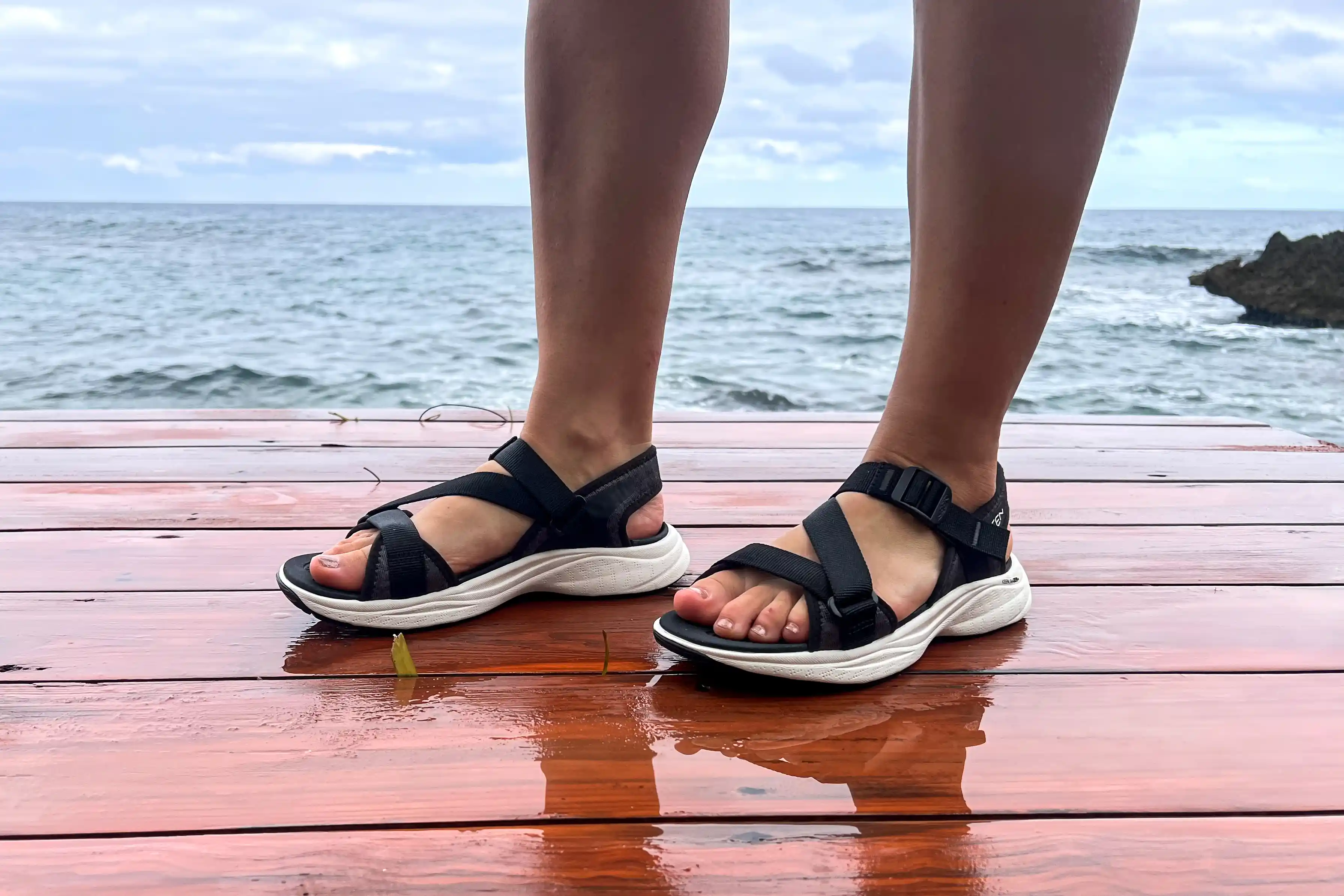 A person's legs close-up while posed in the Keen Women's Leiki Open-Toe Sandal on a dock