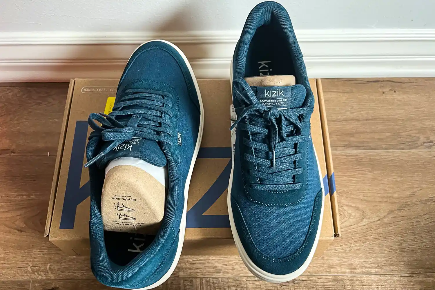 A pair of Kizik Men's Prague 2 Sneakers on a shoebox