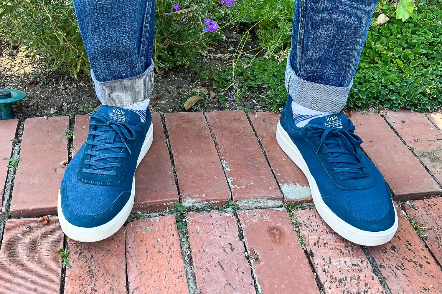 A person wears the Kizik Men's Prague 2 Sneakers outside on brick