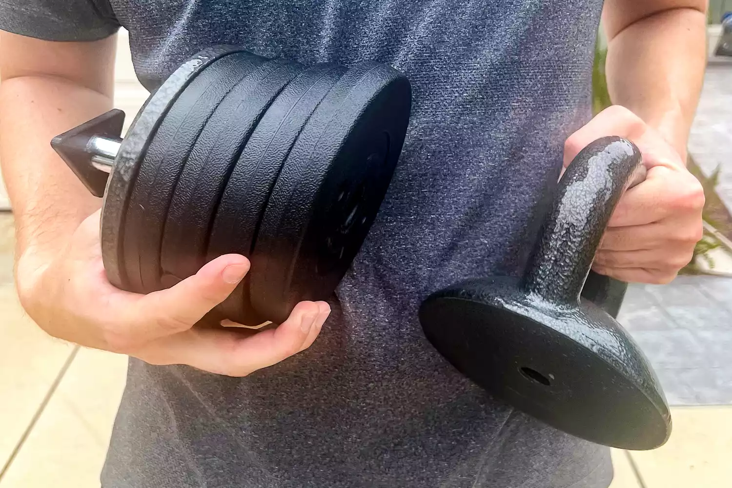 A person holds the weights of the Apex APKB-5009 Adjustable Heavy-Duty Kettlebell