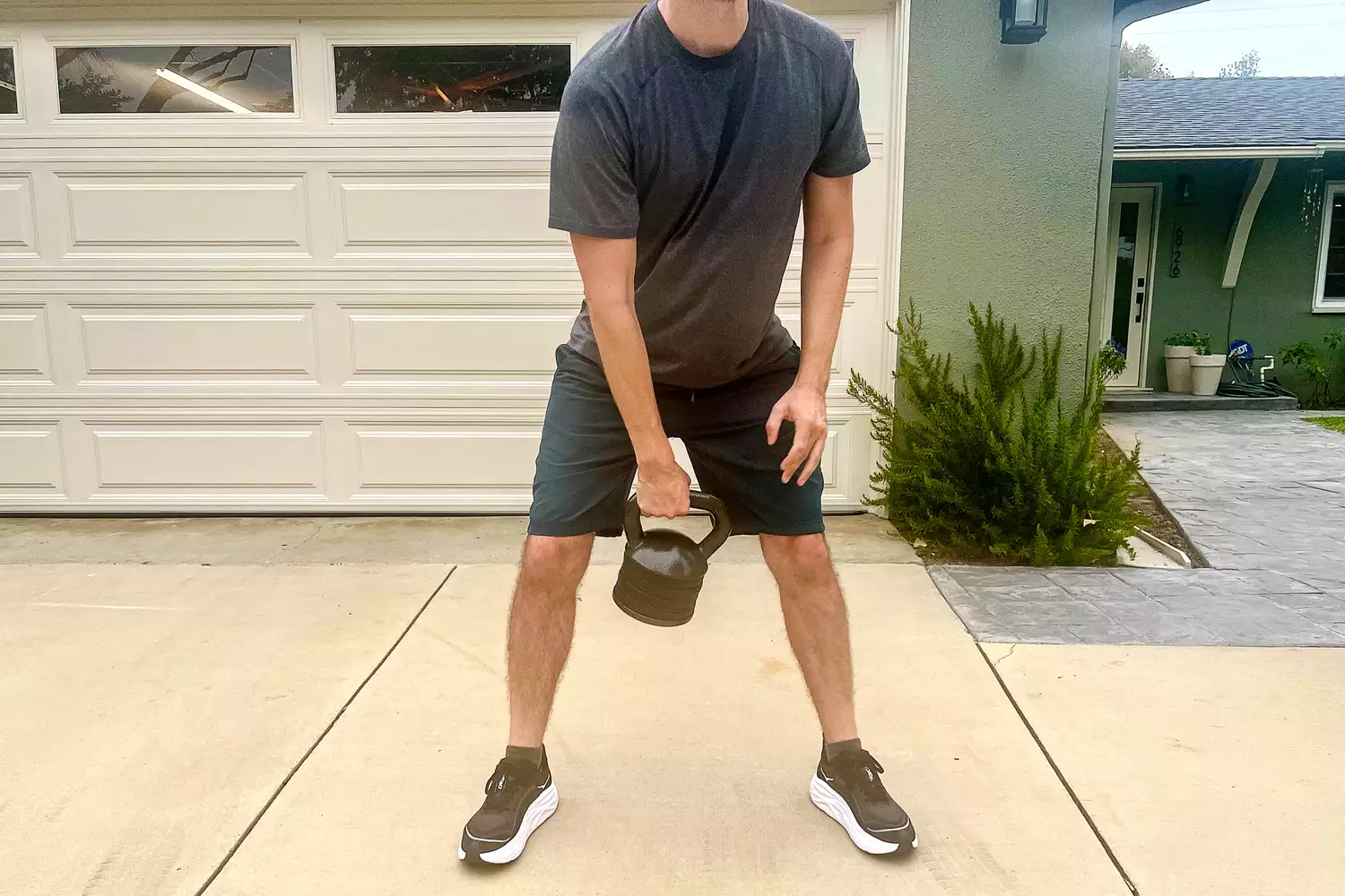 A person lifts the Apex APKB-5009 Adjustable Heavy-Duty Kettlebell Set