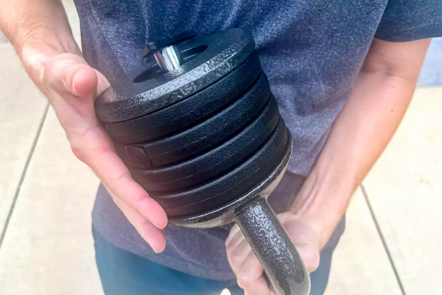 A person adjusts the weights on the Apex APKB-5009 Adjustable Heavy-Duty Kettlebell