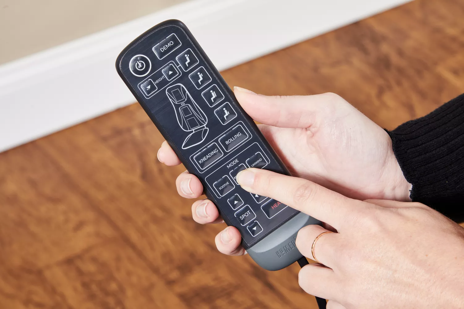 Hands holding the remote controller of a Homedics Shiatsu Elite II Massage Cushion with Heat