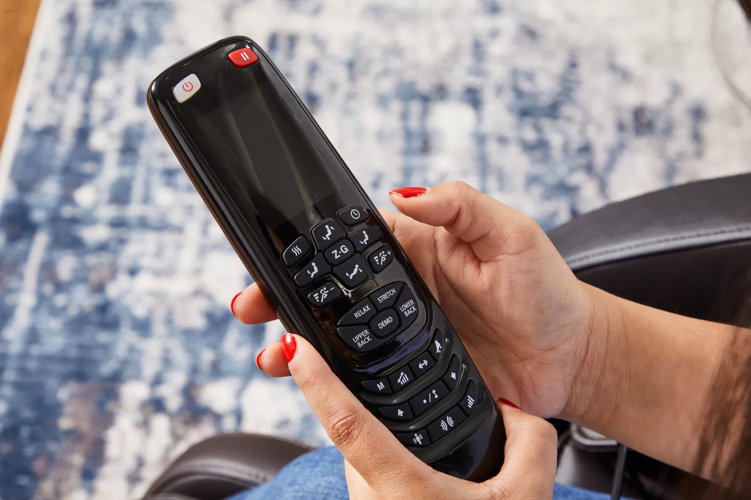 Hands holding the controller of an Osaki OS-Champ Massage Chair