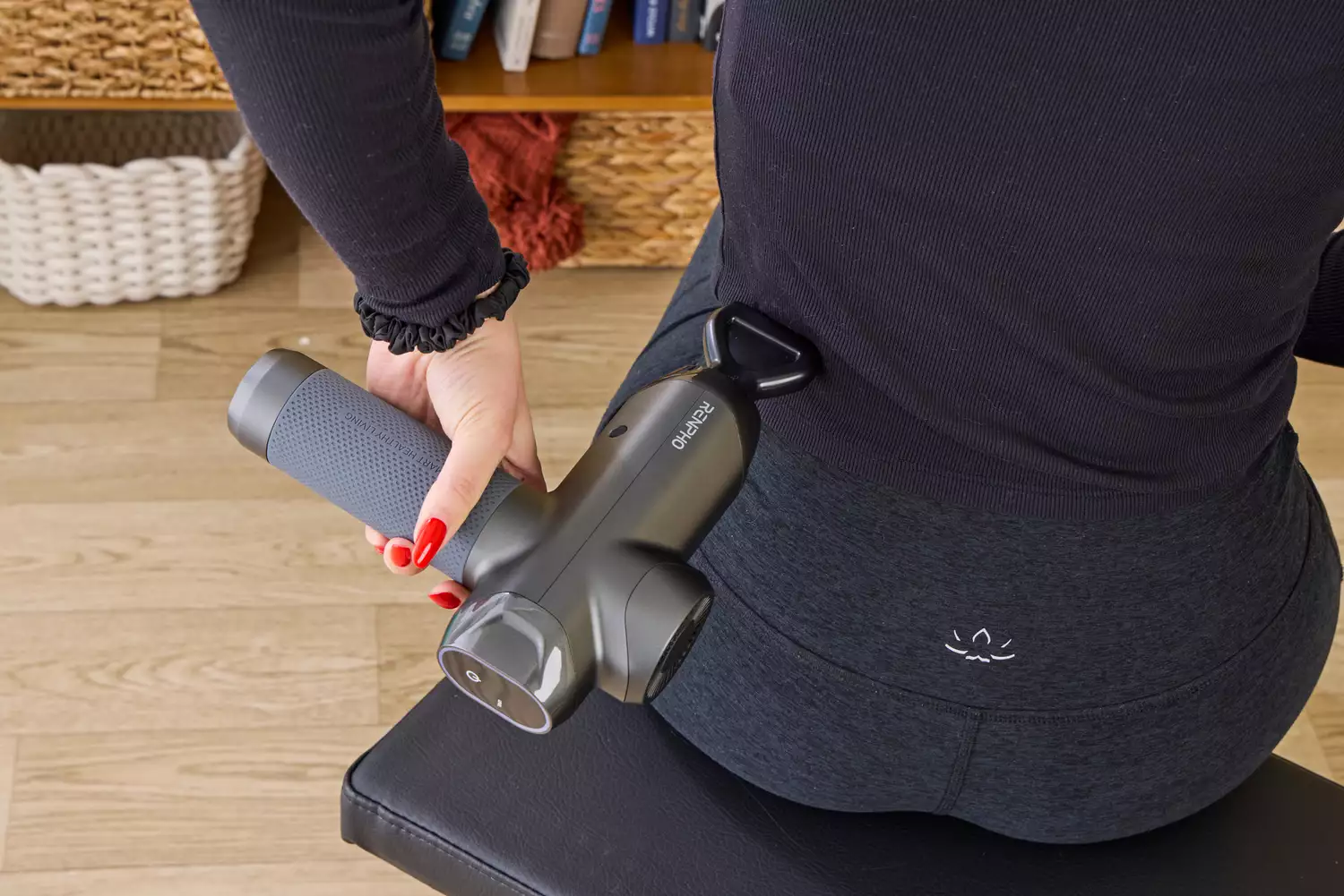 A person using the RENPHO Power Massage Gun on their back