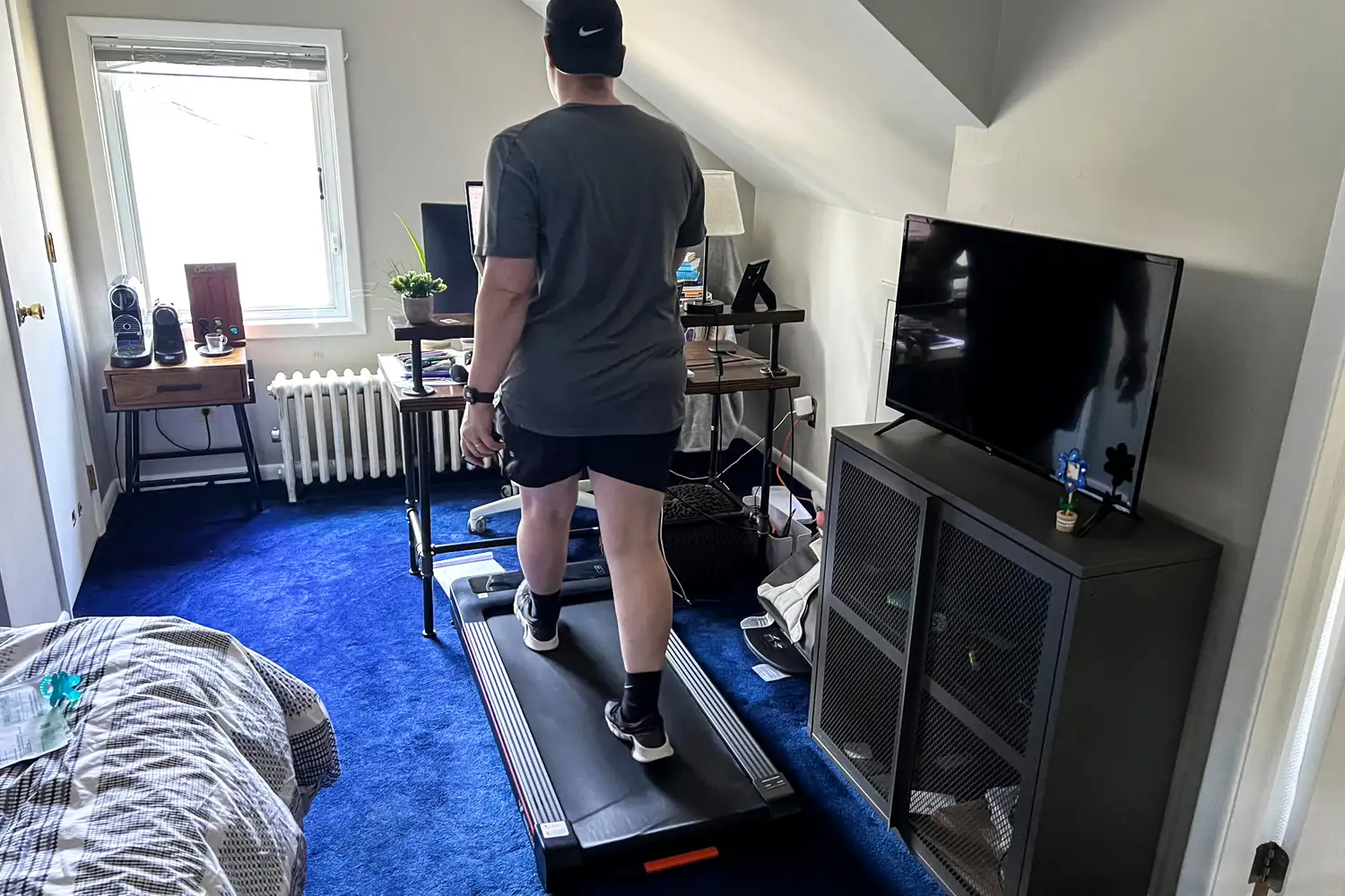 A person walks on the Merach NovaWalk W50 TrekPad with Incline while at a desk