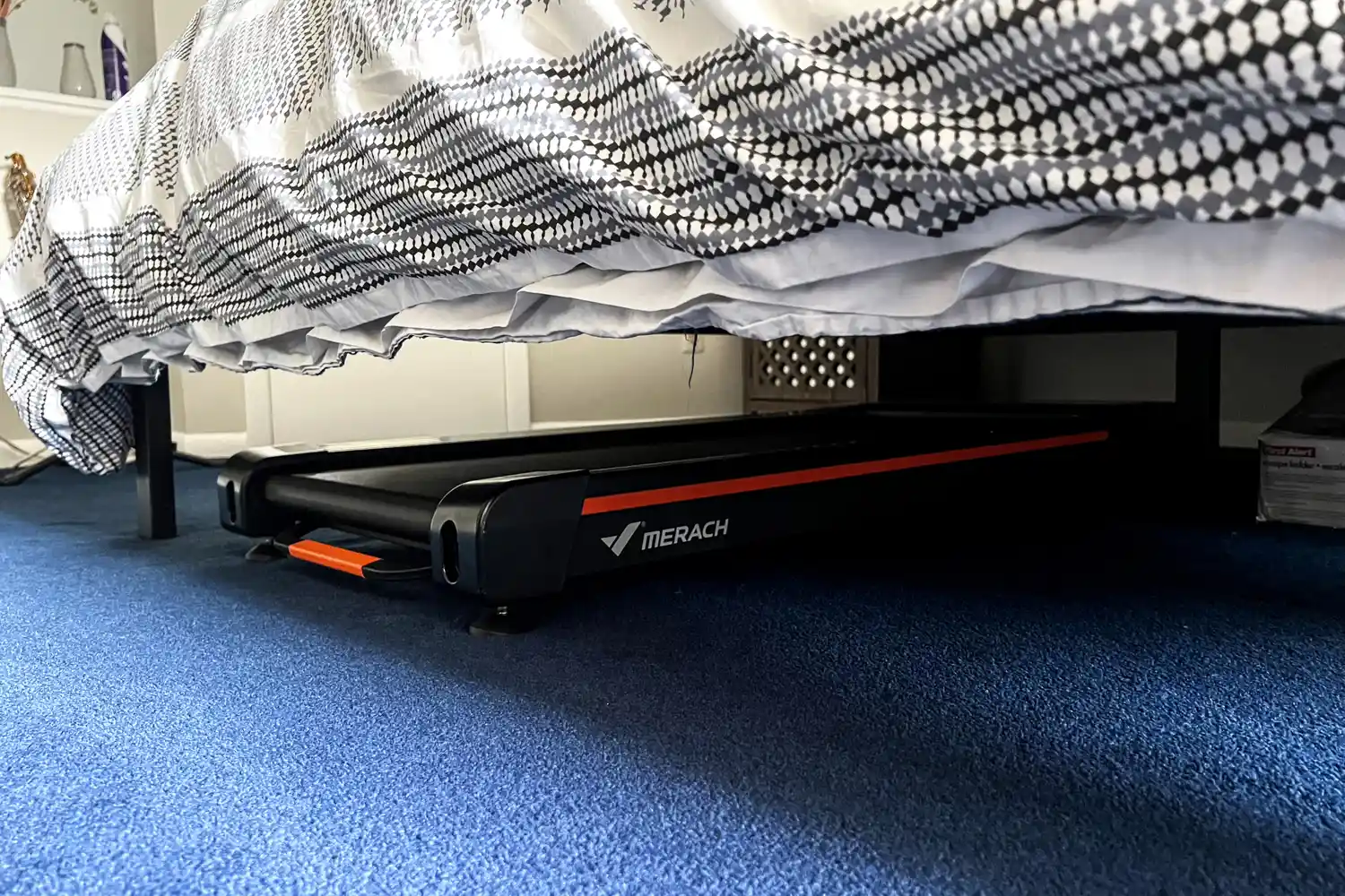 The Merach NovaWalk W50 TrekPad with Incline stored under a bed