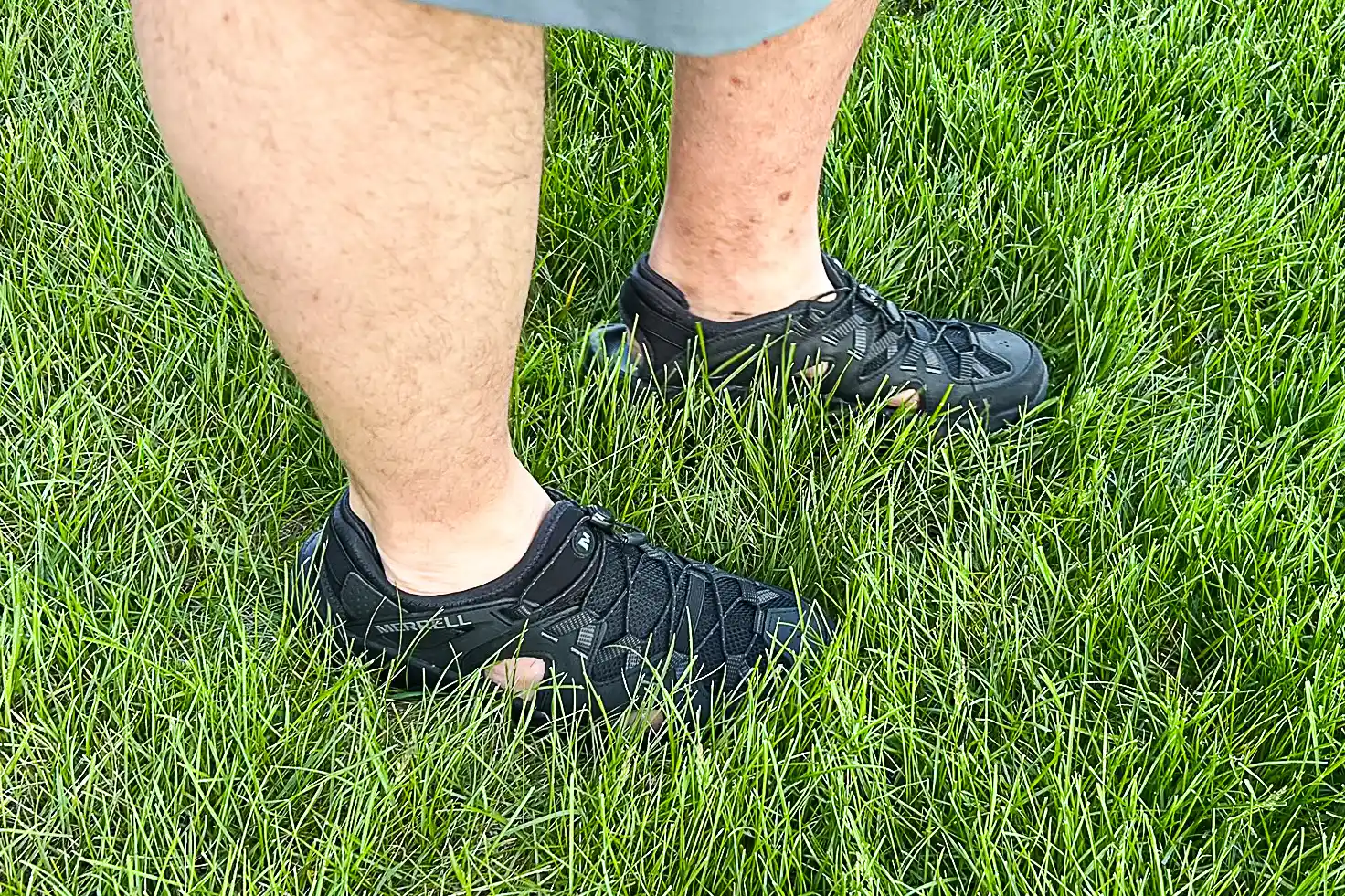 A person walks through grass while wearing the Merrell Men's Maipo Explorer Sieve Shoes