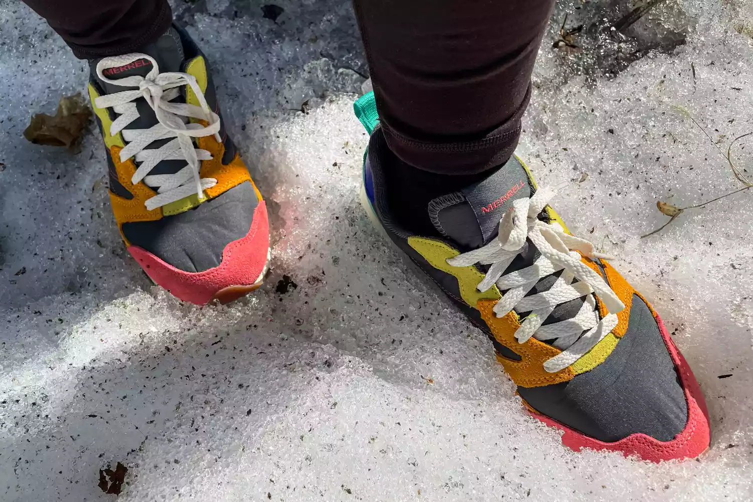 An overhead view of a person's feet wearing the Merrell Women's Alpine 83 Sneaker Sport sneakers in snow
