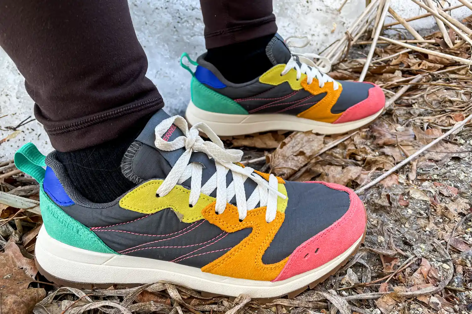 A close-up of a person's feet wearing the Merrell Women's Alpine 83 Sneaker Sport on dirt