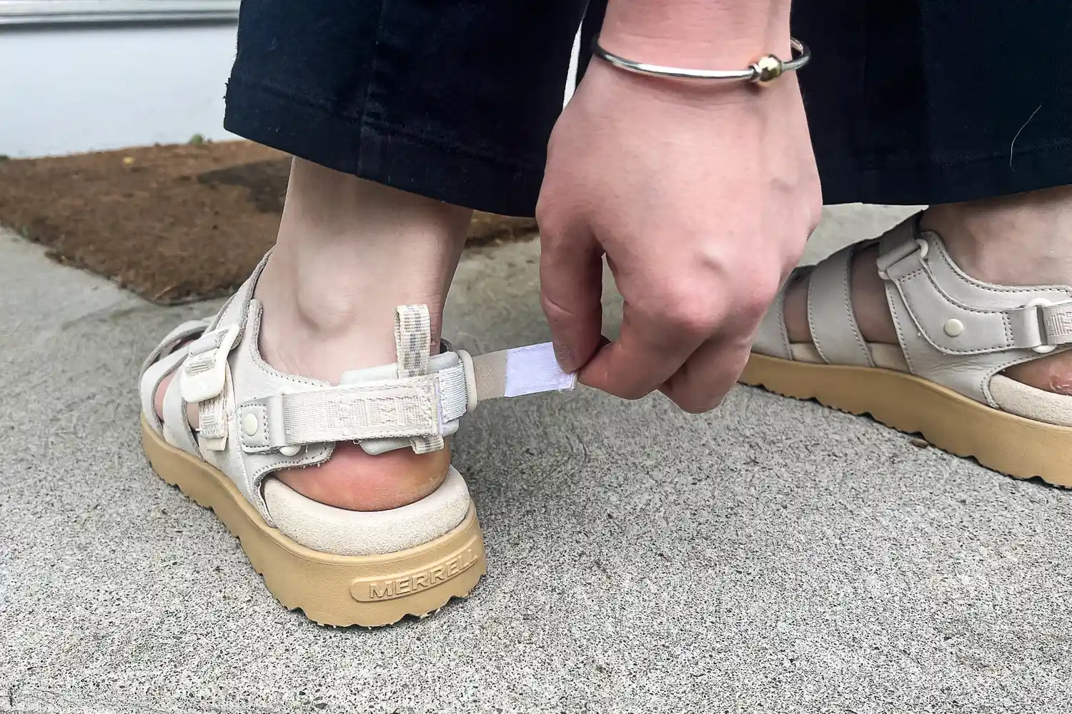 A person tightens the heel strap on the Merrell Women's Fleur Fisherman Sandal