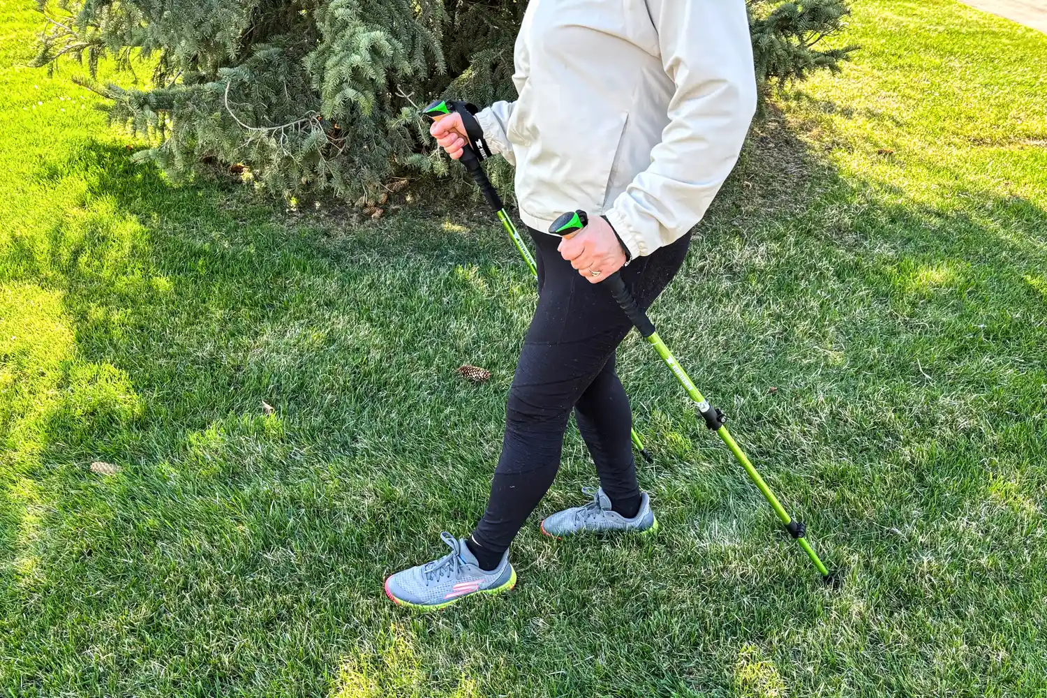 A person walks through grass using the Mountainsmith Tellurite 7075 OLS Trekking Poles