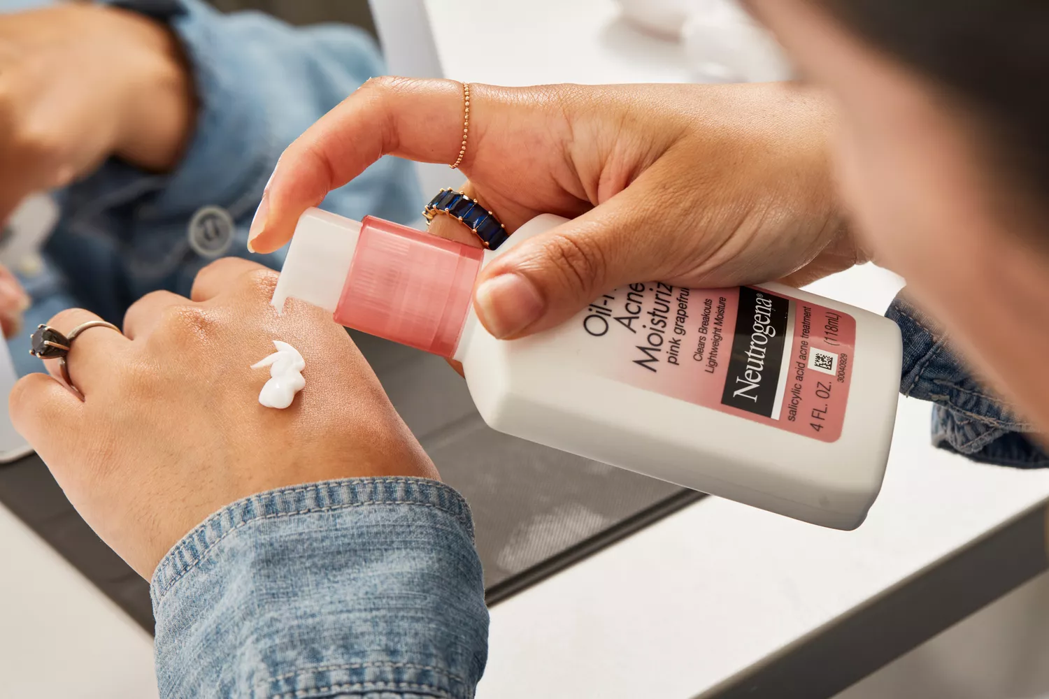 Person applying Neutrogena Pink Grapefruit Oil-Free Acne Moisturizer to the back of their hand