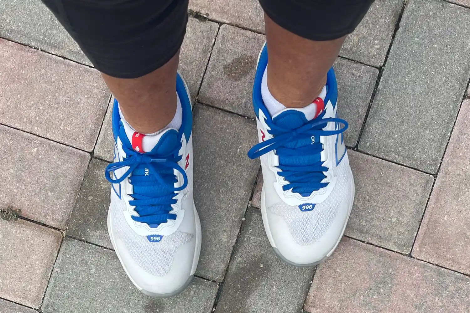 A person wears the New Balance Women's FuelCell 996v6 Pickleball Shoes on brick