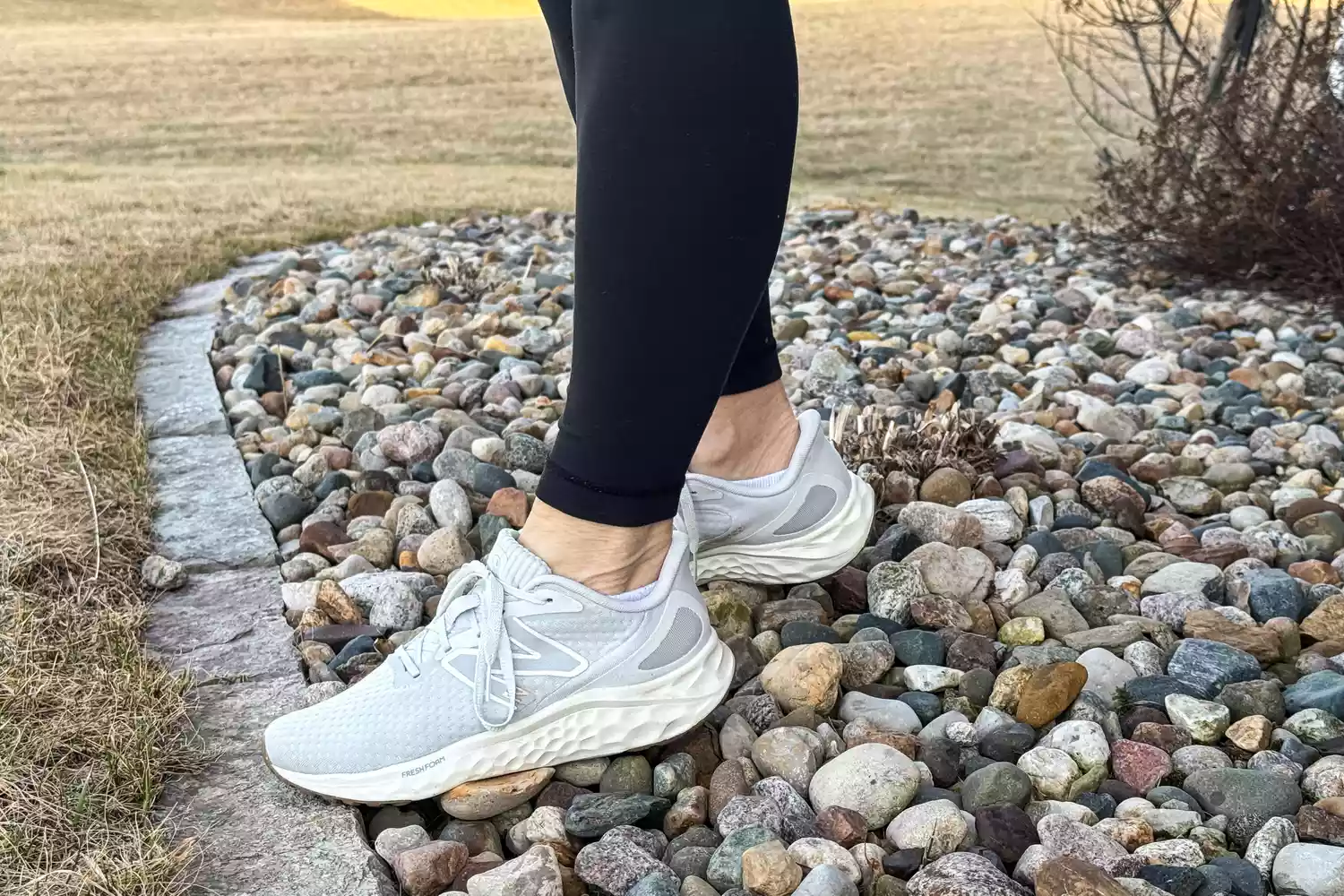 A close-up of the New Balance Women's Fresh Foam Arishi v4 sneakers worn on stones