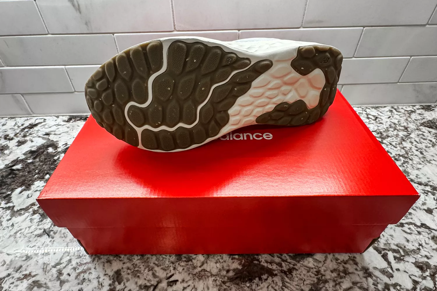 A New Balance Women's Fresh Foam Arishi v4 posed on its box to show the bottom of the shoe